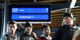 Flüchtlinge gehen ein Gleis auf dem Flensburger Bahnhof entlang.