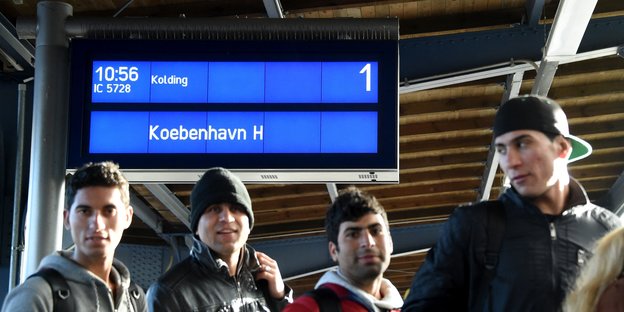 Flüchtlinge gehen ein Gleis auf dem Flensburger Bahnhof entlang.