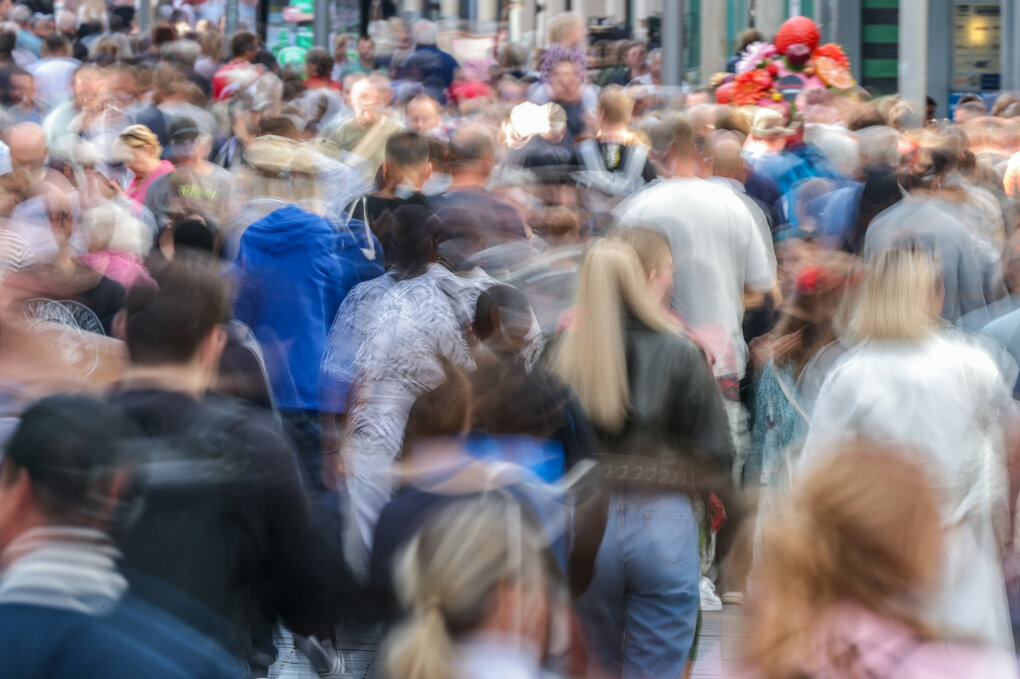 Zahlreiche nur unscharf zu sehende Passanten auf einer Straße