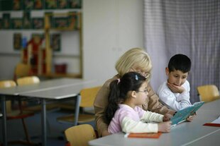 Eine Frau liest zwei Kindern aus einem Buch vor