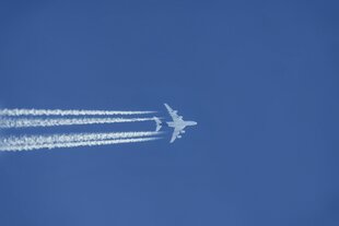 Ein Flugzeug am Himmel zieht Konsensstreifen hinter sich her