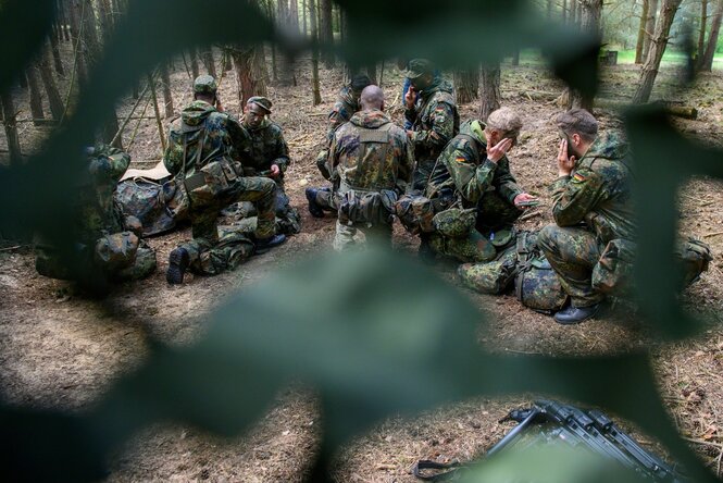 Soldaten schmieren sich Tarnfarbe in ihre Gesichter