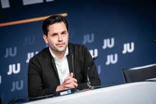 Ein Mann sitzt an einem Tisch mit Mikrofon