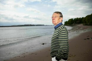 Ein Mann steht am Strand und schaut auf einen Fluss