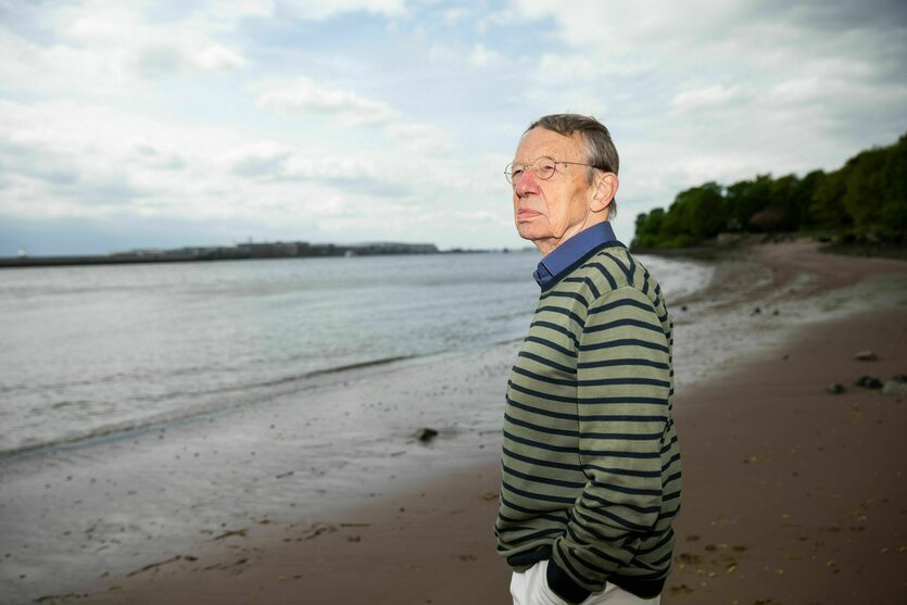 Ein Mann steht am Strand und schaut auf einen Fluss