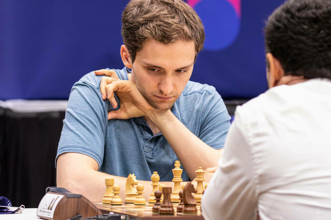 Schachspieler stützt seinen Kopf auf Handgelenk auf und schaut auf das Brett