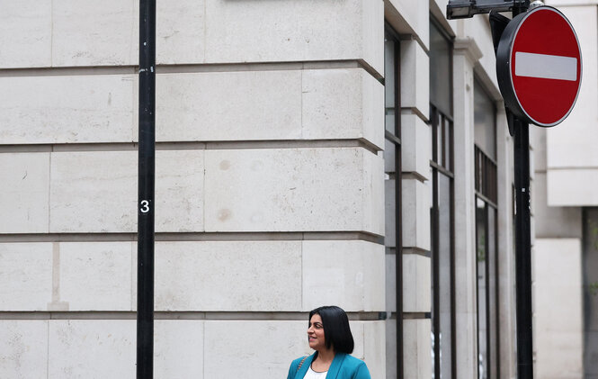 Eine Frau vor einer Hauswand blickt nach rechts. Über ihr ein Einbahnstraßenschild