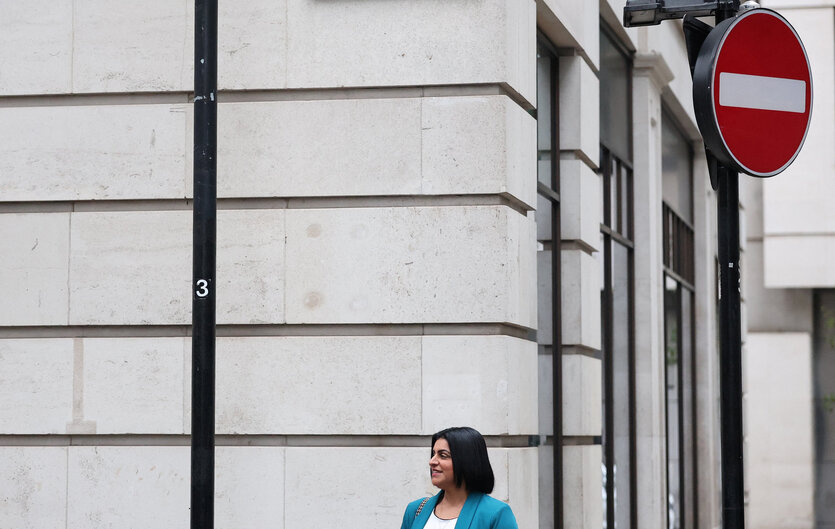 Eine Frau vor einer Hauswand blickt nach rechts. Über ihr ein Einbahnstraßenschild