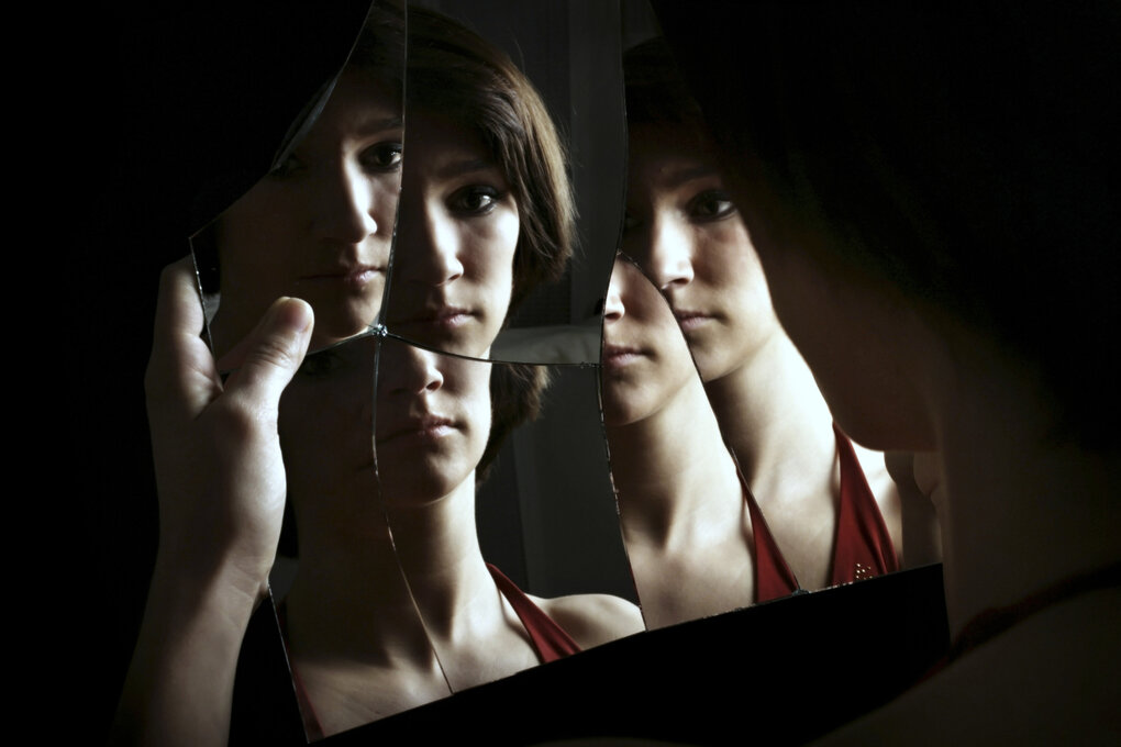 Eine Frau spiegelt sich in einem Kaputten Spiegel