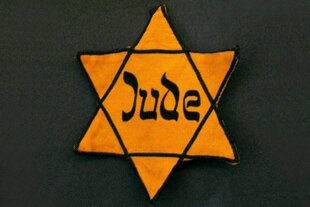 Ein gelber Judenstern auf dunklem Grund