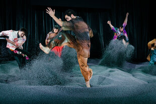 Bunt kostümierte Schauspieler bewegen sich durhc ein graues Meer aus Styropor.
