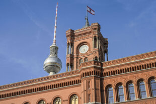 Das Foto zeigt das Rote Rathaus in Berlin und dahinter den oberen Teil des Fernsehturms.