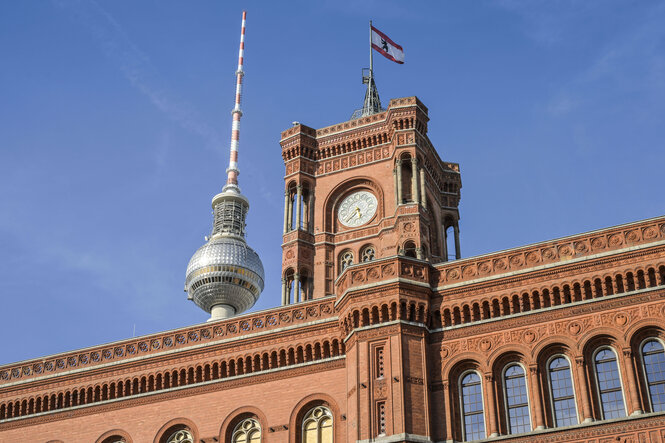 Das Foto zeigt das Rote Rathaus in Berlin und dahinter den oberen Teil des Fernsehturms.