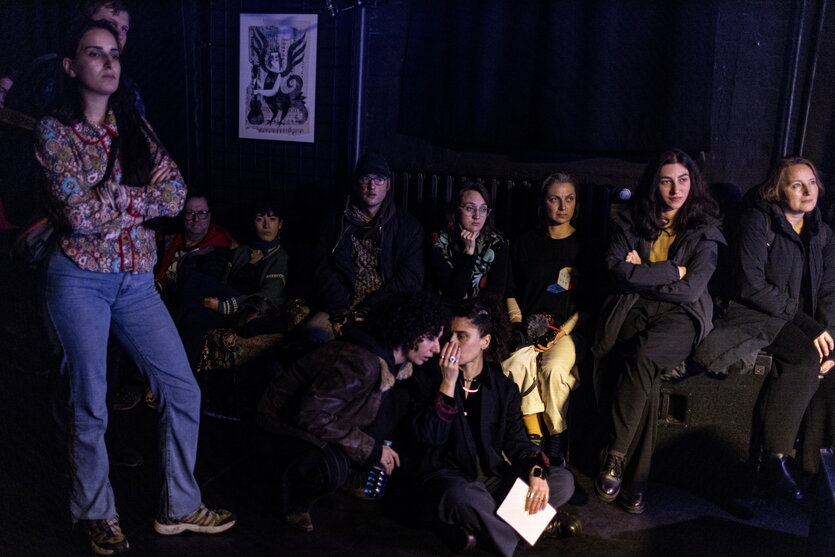 eine Gruppe von Menschen sitzt im Dunklen und hört aufmerksam zu