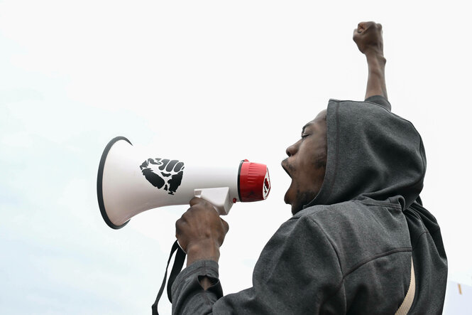 Eine Person mit Megafon bei einer Demonstration.