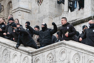 Gestikulierende schwarz gekleidete Personen auf einer Treppe.