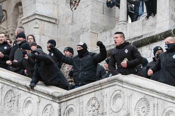 Gestikulierende schwarz gekleidete Personen auf einer Treppe.
