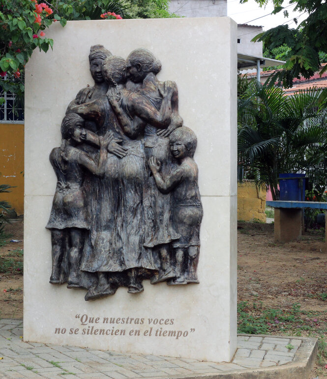 Ein Bronzerelief in der Ciudad de las Mujeres zeigt, ineinander verschlungen, Frauen und Mädchen aus Bronze, die einen Kreis bilden und sich so gegen Angreifer und den Betrachter abschotten