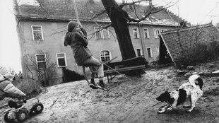 Ein historisches Bild zeigt einen Hof mit spielenden Kindern.