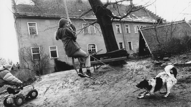 Ein historisches Bild zeigt einen Hof mit spielenden Kindern.