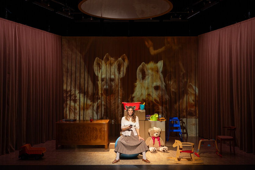 Eine Frau mit Hyämnenohren sitzt zwischen Kinderspielzeug