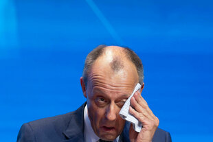Bundeskanzler Friedrich Merz wischt sich Schweißz vom Kopf.