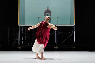Ein Mann in rot-weißer Toga tanzt auf der Bühne