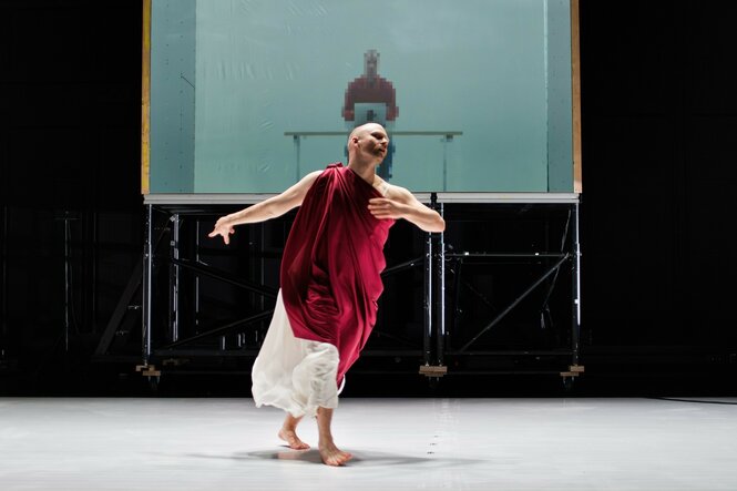 Ein Mann in rot-weißer Toga tanzt auf der Bühne