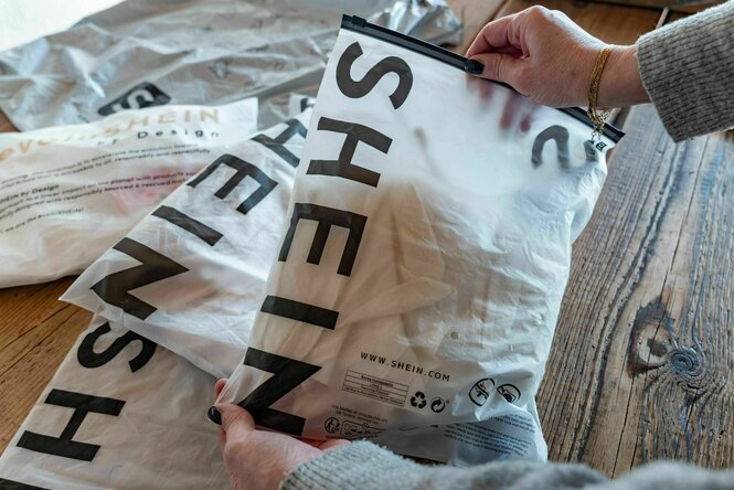 Eine Person hält Plastikverpackungen von der Fastfashion-Firma SHEIN in den Händen