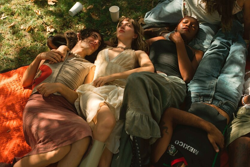 Junge Menschen liegen auf einer Wiese und schauen in den Sommerhimmel