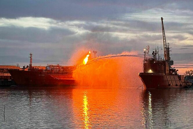 Ein brennender Tanker in einem Hafen.