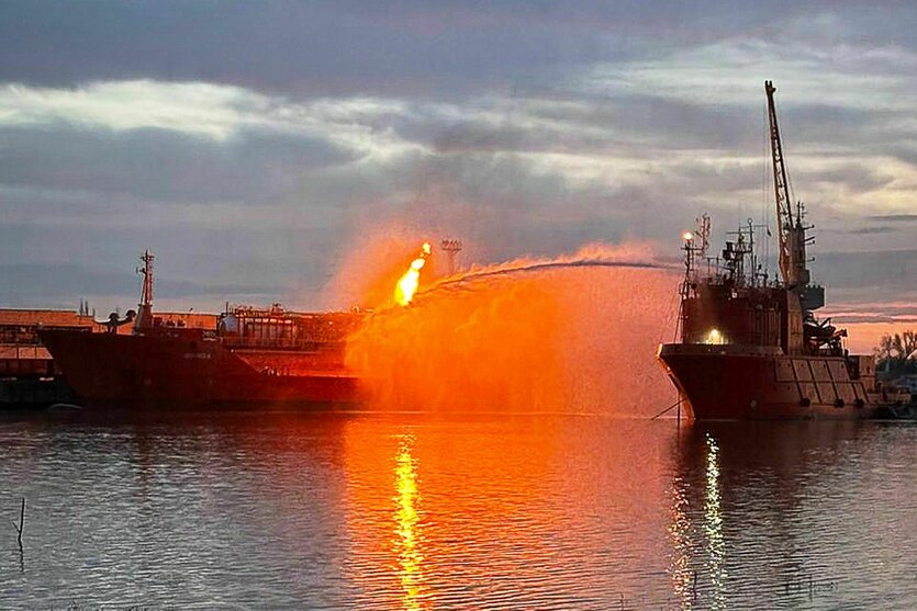 Ein brennender Tanker in einem Hafen.
