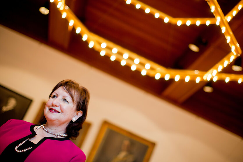 Seyla Benhabib blickt lächelnd nach oben, an der Decke hängen Glühbirnen