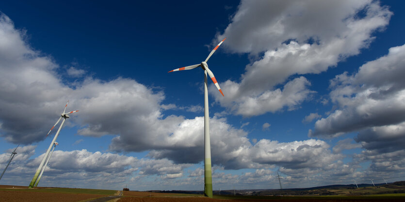 Windräder stehen vor einem blauen Himmel, über den Wolken ziehen