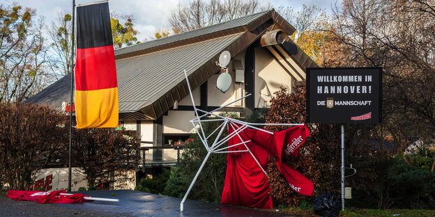 Vor einem Haus steht eine Deutschlandfahne, daneben ein kaputter Sonnenschirm