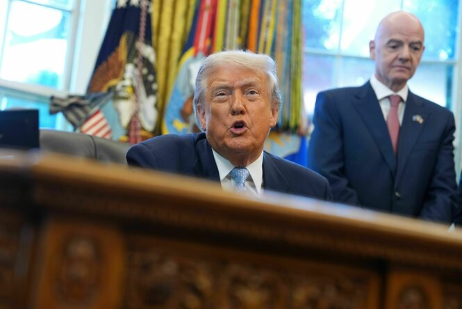 Donald Trump an seinem Schreibtisch. Dahinter Fifa-Präsident Gianni Infantino