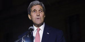 John Kerry steht vor einem Mikrofon