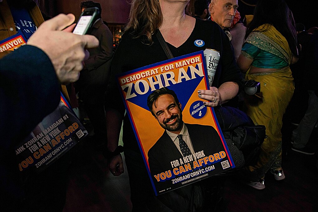 Eine Person hält ein Wahlplakat in den Händen, welches das Porträt eines Mannes zeigt