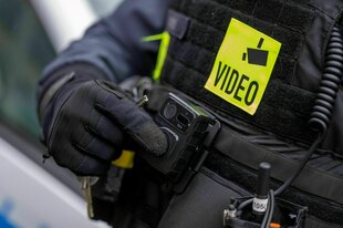 Ein Polizist schaltet die Bodycam auf seiner Uniform ein