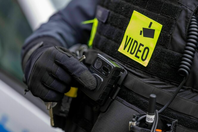 Ein Polizist schaltet die Bodycam auf seiner Uniform ein