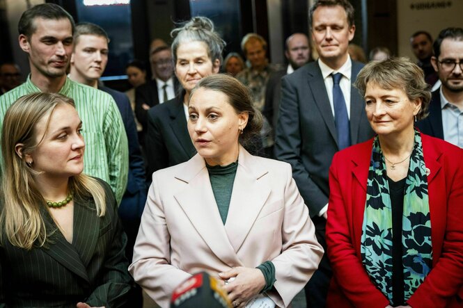 Personen stehen in zwei Reihen hintereinander, in der vorderen Reihe drei Frauen