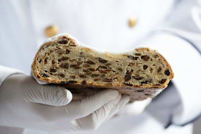 Stollenprüfer hält ein Stück Stollen in seinen Handschuh-Händen