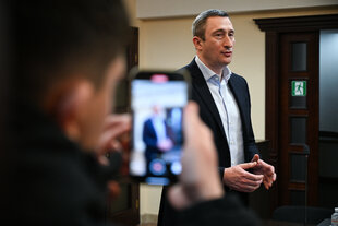 Ein Mann im Anzug spricht mit Vertretern der Presse