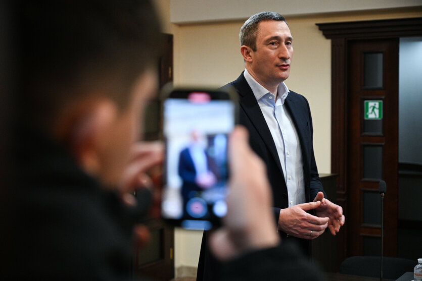 Ein Mann im Anzug spricht mit Vertretern der Presse