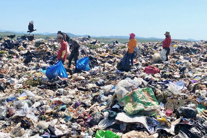 Mehrere Menschen auf einer Müllkippe.