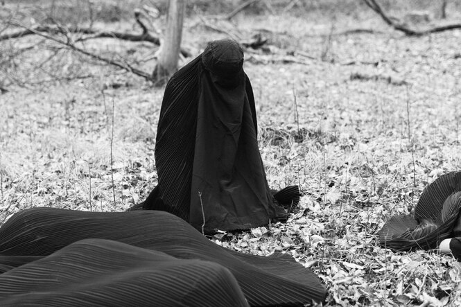 Schwarz-weiß Foto einer knienden Frau in Burka.