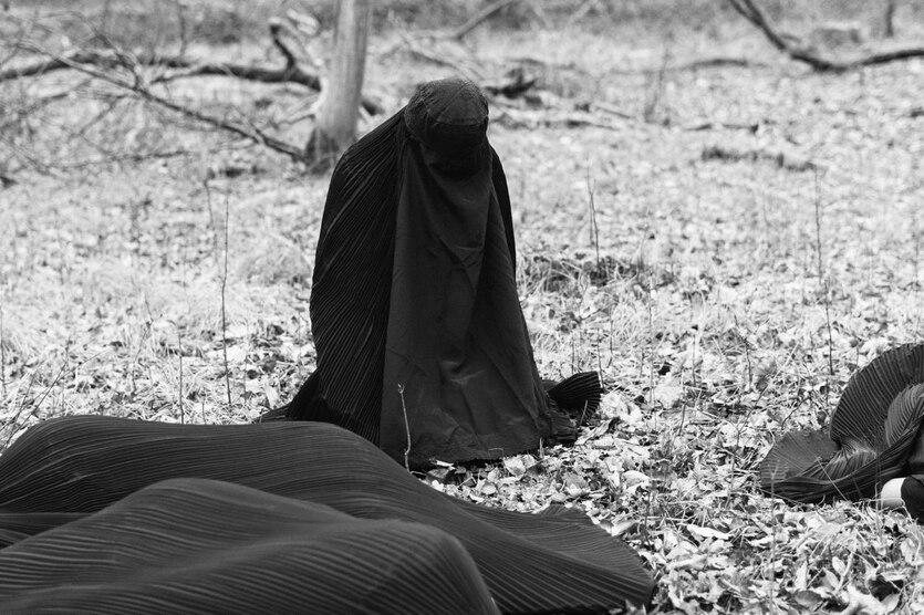 Schwarz-weiß Foto einer knienden Frau in Burka.