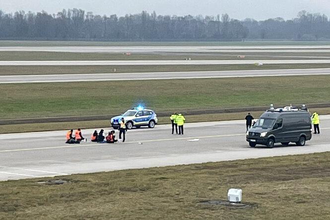 Aktivist:innen blockieren eine Landebahn.