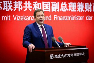 Ein Mann steht an einem Rednerpult und spricht ins Mikrofon