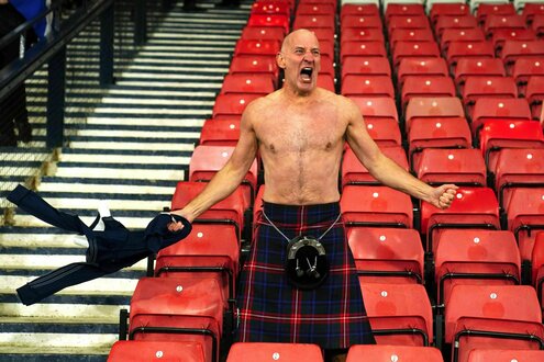 Ein Fan mit nacktem Oberkorper im Schottenrock schreit vor Freude auf der Stadiontribüne